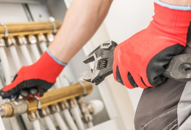 AdobeStock_258801370 (Niestandardowy)-min pracownik montujący instalację ogrzewania